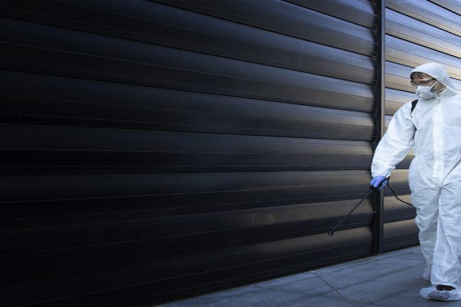 Hombre vestido con EPI blanco para controlar una plaga en un local