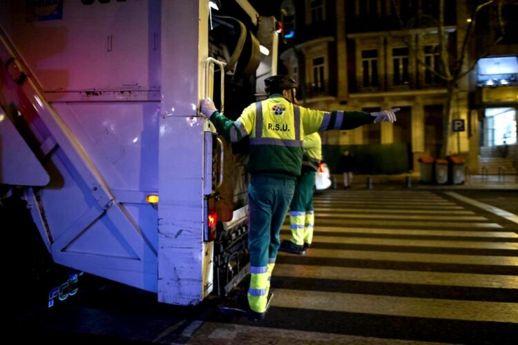 Dos empleados de recogida de basura con uniforme amarillo y verde y las siglas RSU junto a un camión blanco del servicio de limpiezas