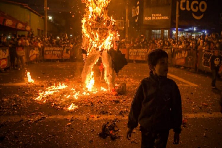 Una figura representando al Diablo ardiendo tras un niño en primer plano a la derecha