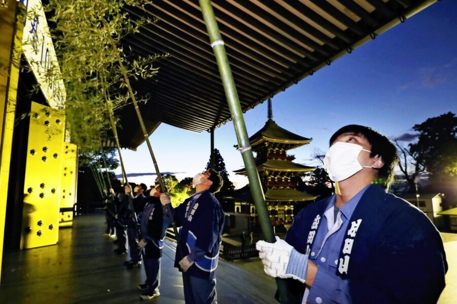 Limpiadores japoneses con mascarilla usan cañas de bambú para limpiar un templo.