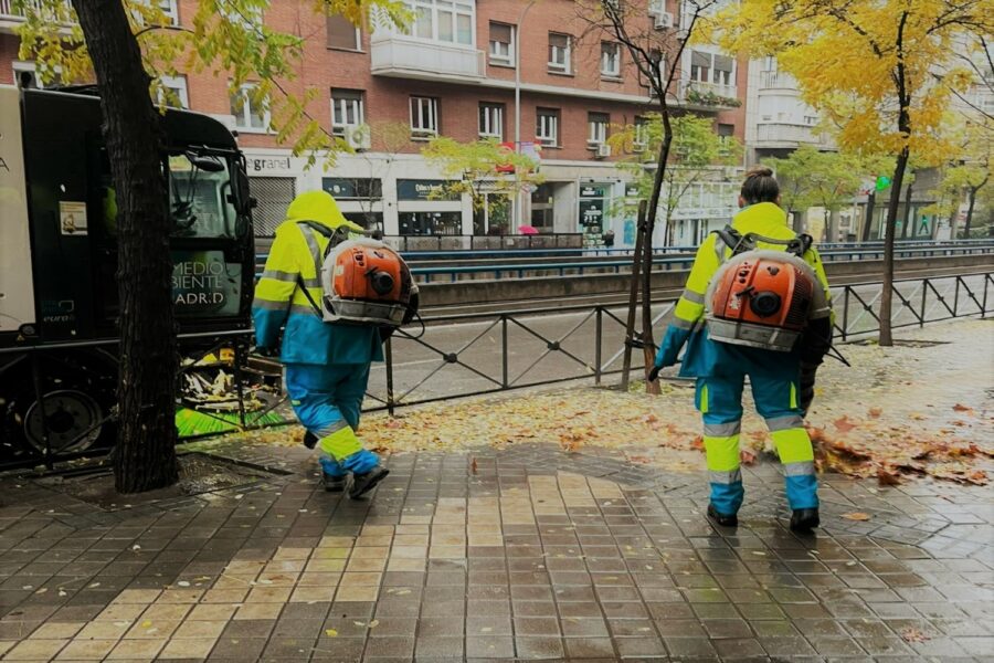 Dos operarios uniformados de amarillo y azul con mochila naranja limpian las calles de Madrid