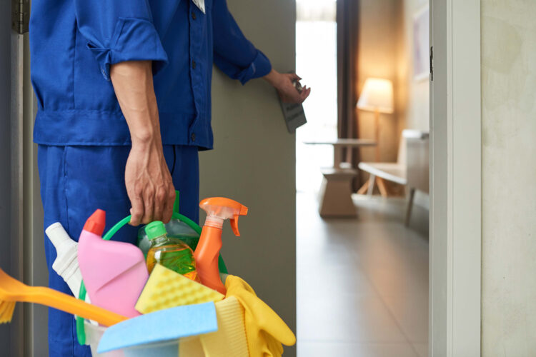 Trabajador entrando a una habitación con un kit de limpieza.