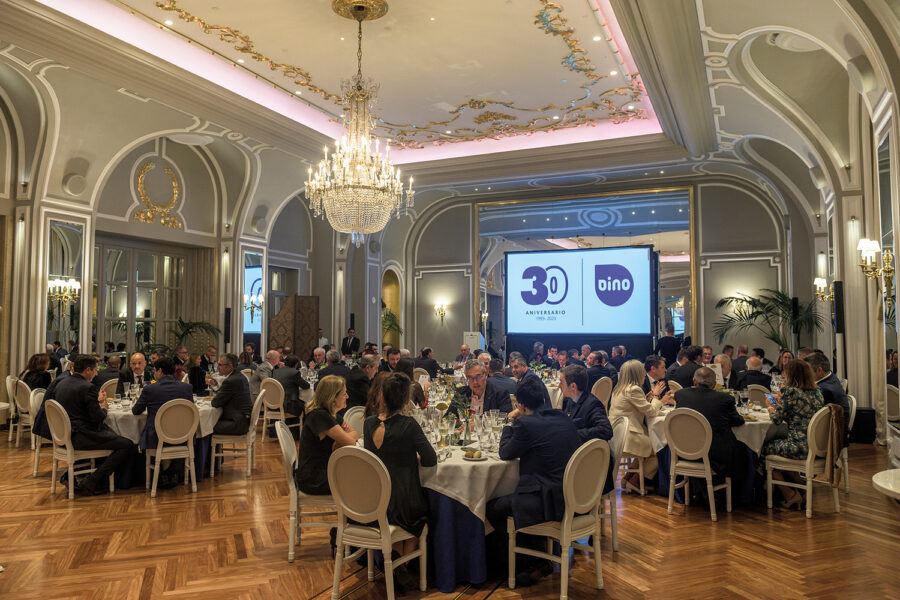 mesas redondas con gente con proyector de fondo con el logo de Dino 30 aniversario