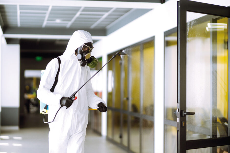 Disinfecting of office to prevent COVID-19, Man in protective hazmat suit with with spray chemicals to preventing the spread of coronavirus, pandemic in quarantine city. Cleaning concept.